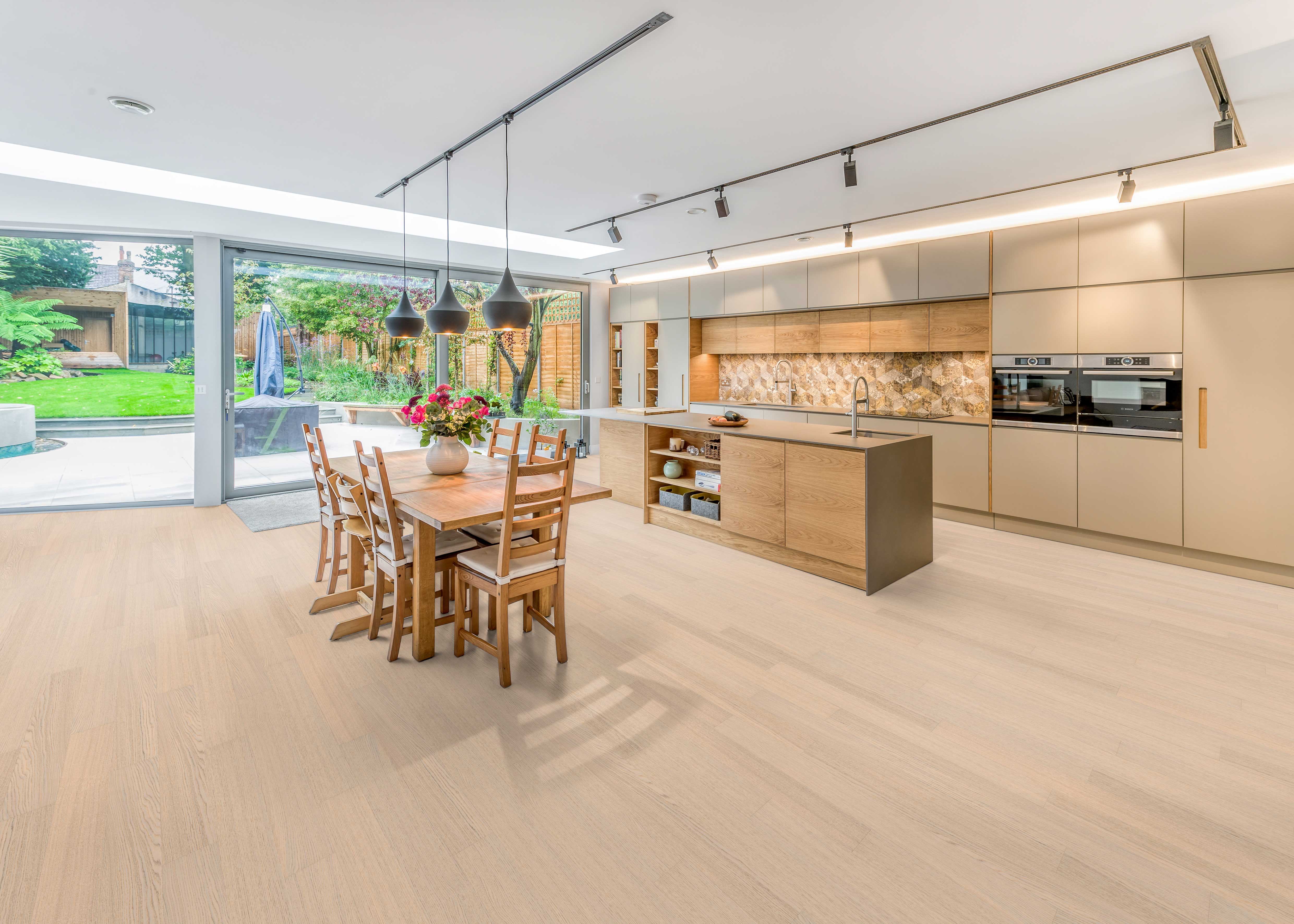 Moderne Küche mit Essbereich und hellem Bodenbelag in Holzoptik, Akzentwand mit geometrischem Muster und Wandabschluss.