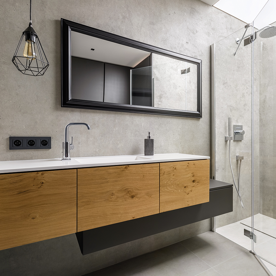 Badezimmer mit Waschtischunterschrank in Holzoptik, Steinoptik Wand und Glasduschkabine für moderne Raumgestaltung.
