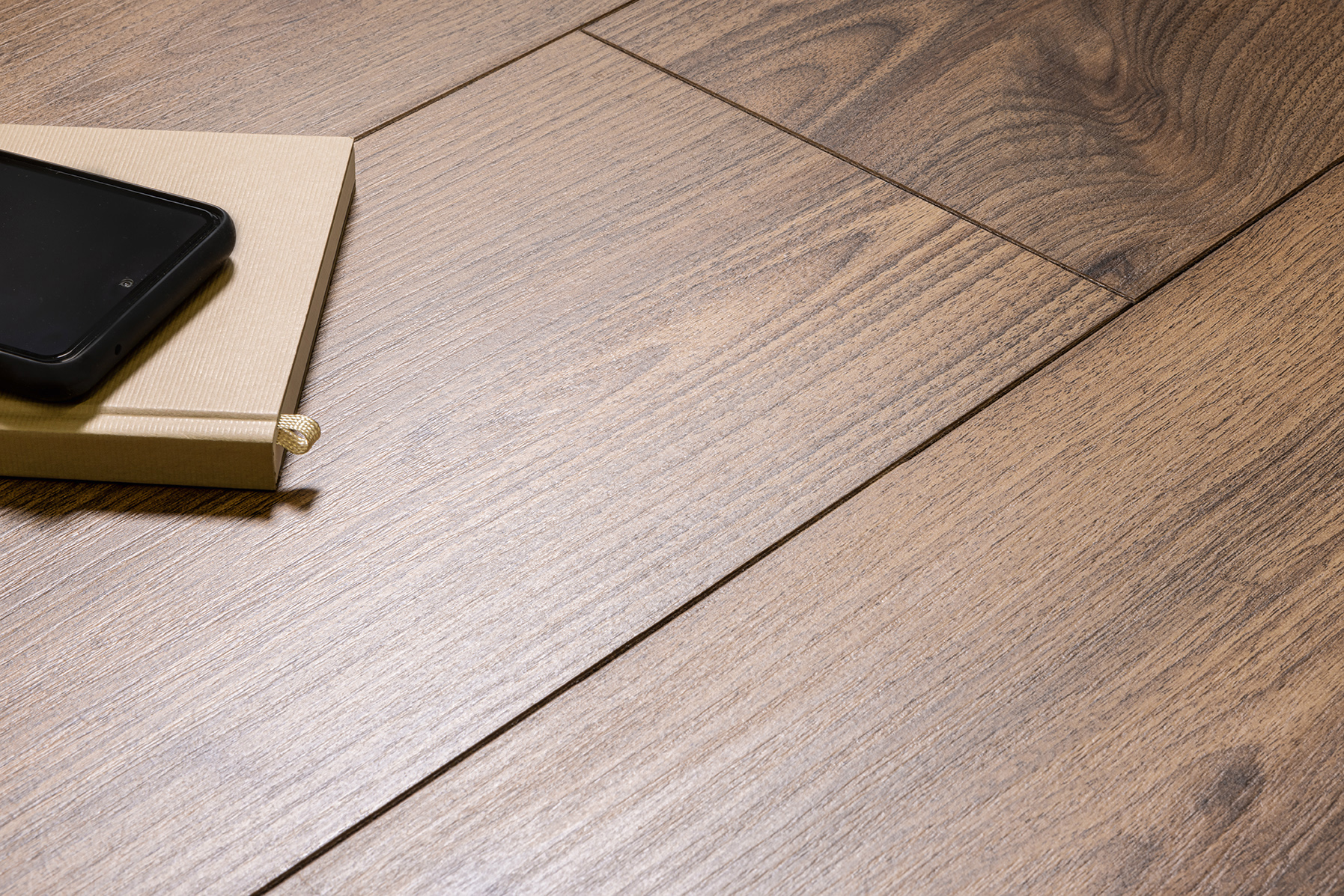 Holzoptik Bodenbelag mit strukturierter Maserung und einem aufgeschlagenen Buch mit Smartphone darauf