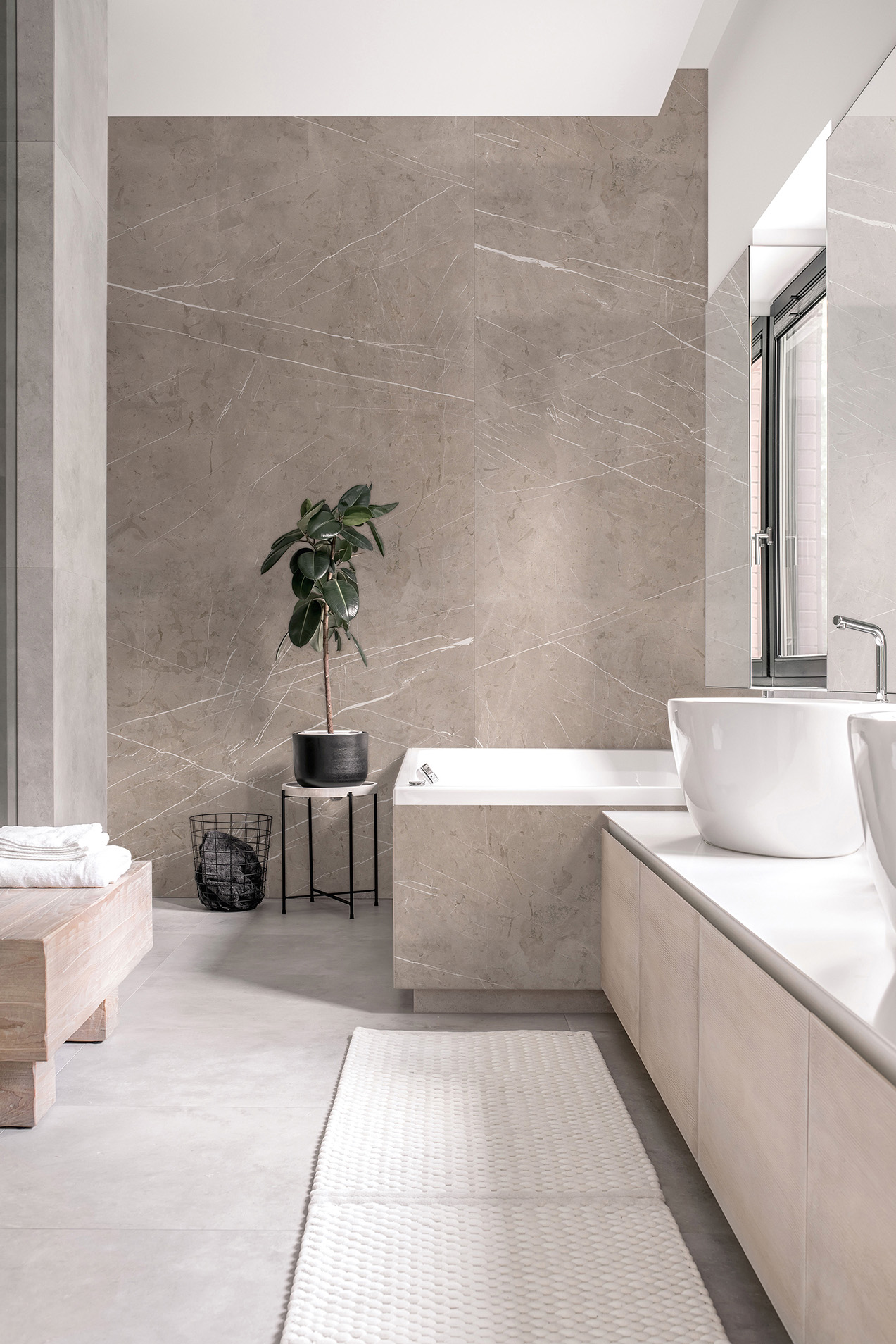 Moderne Raumgestaltung mit Bodenbelag in Steinoptik und akzentuierter Wandgestaltung in Marmoroptik, mit Badewanne und Waschbecken.