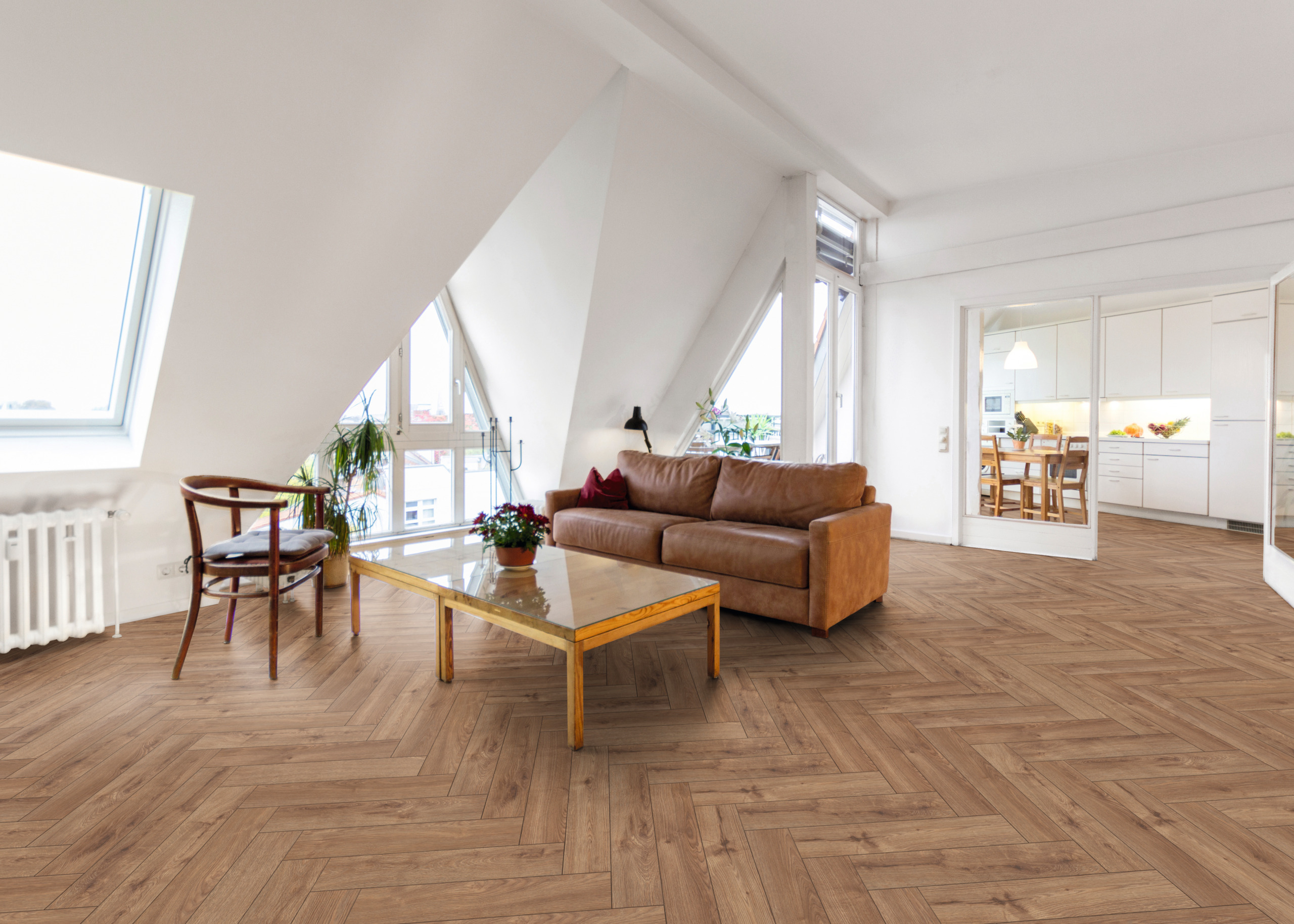 Moderne Raumgestaltung mit Holzoptik Bodenbelag im Fischgrätmuster, brauner Ledersofa, Glastisch und offener Küche.