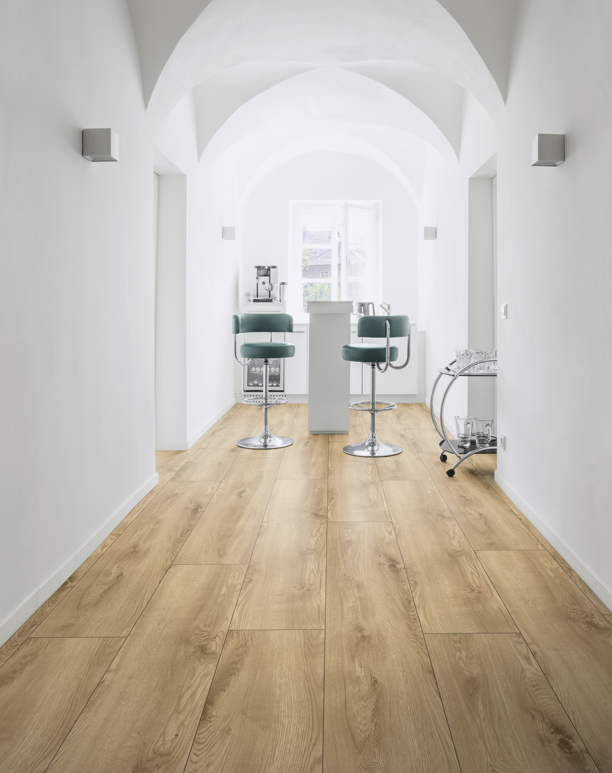 Lichtdurchfluteter Raum mit Holzbodenoptik, Barhocker und Küchentresen, ideal für Raumgestaltung und Wandabschluss.